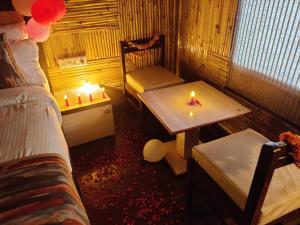 斋浦尔Hotel Bamboo Castle的配有桌子、椅子和蜡烛的房间