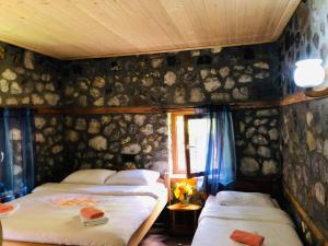瓦勒博内Guest house Hyrmet Demushi的一张位于岩石墙的房间里,设有两张床