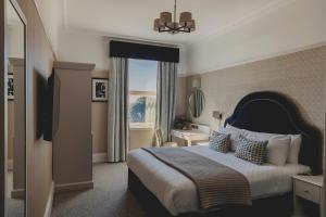 朴次茅斯The Queens Hotel的一间卧室设有一张大床和一个窗户。
