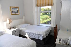 穆林加尔Railway House Guest House的酒店客房设有两张床和窗户。