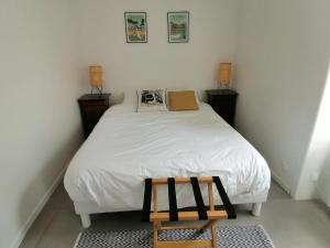 奥雷龙圣皮耶尔Le Chai de Saint-Pierre的一间小卧室,配有白色的床和木凳