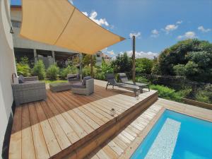 舍尔谢Kozycoco - Suite Kozy - séjour tropical au calme的一个带遮阳伞和游泳池的木制甲板