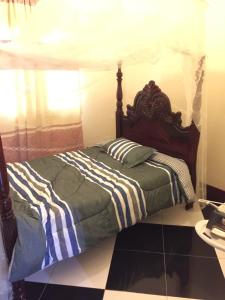 坎帕拉HEDGE GUEST HOUSE的一间卧室配有一张带木制床头板的床