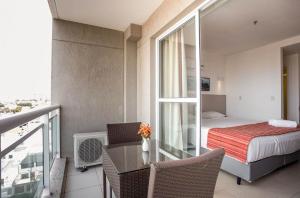 马卡埃Flat 804 - Conforto e vista panorâmica em Macaé的客房设有带一张床和一张桌子的阳台。