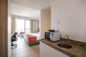 马卡埃Flat 804 - Conforto e vista panorâmica em Macaé的酒店客房设有一张床和一个带水槽的厨房