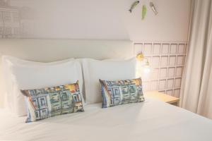 里斯本Mouraria Lisboa Hotel的一张带两个枕头的白色床和白色床头板