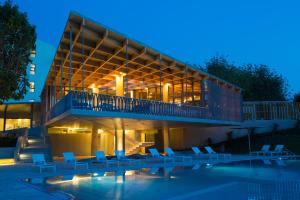 塔维拉OZADI塔维拉酒店 的一座带椅子的建筑和一座夜间游泳池