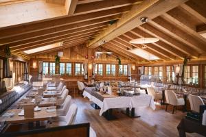 格施塔德Hôtel de Rougemont & Spa的餐厅设有木制天花板和桌椅