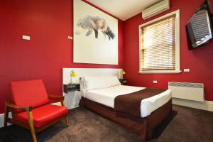 墨尔本托拉诺酒店的红色卧室配有床和红色椅子