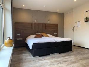 Varsseveld德普罗格霍恩餐厅酒店的一间卧室配有一张大床和木制床头板