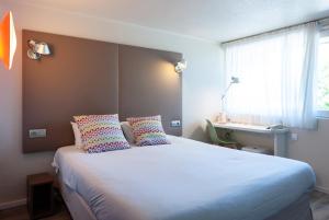 博讷钟楼宝纳酒店的卧室配有带枕头的白色床和窗户。