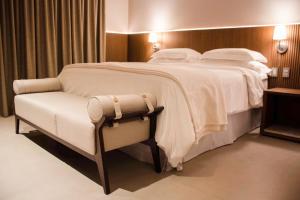 库亚巴Amazon Taiamã Hotel的一张大床,位于酒店带椅子的房间里