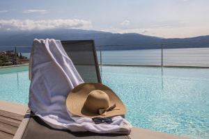 托斯科拉诺-马德尔诺Exclusive Villa Agave的坐在游泳池旁椅子上的帽子