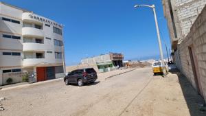 圣胡安Ensenada Hotel的停在建筑物旁边的土路上的车辆