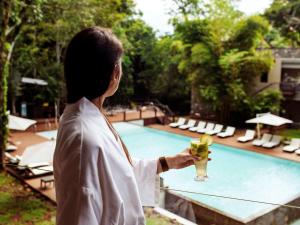 伊瓜苏港伊瓜苏美居伊露酒店的女人在游泳池前喝一杯