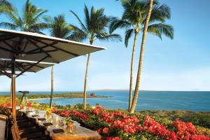拉奈城拉奈岛四季度假酒店的一张桌子,上面有鲜花和棕榈树,还有大海