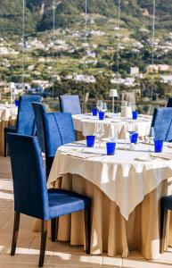 伊斯基亚圣蒙塔诺Spa度假酒店 的一间设有蓝色椅子的餐桌的餐厅,享有美景