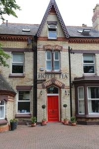 利物浦Hotel Tia的砖砌车道上带红门的砖砌建筑
