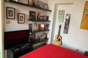 米兰Appartamento splendido con tutti servizi in zona Navigli的一间卧室配有一张床、一台电视和吉他。