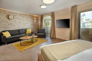 萨法德Romano Hotel Boutique的一间卧室配有一张床、一张沙发和一台电视。
