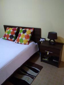 路易港Manuel's Apartment的一张带色彩缤纷枕头的床和一个带桌子的床头柜