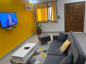 圣路易斯Gîte Le Toubé的带沙发的客厅和黄色墙壁上的电视