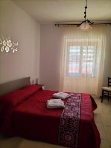 TerralbaB&b la Fenice的一间卧室配有红色的床和毛巾