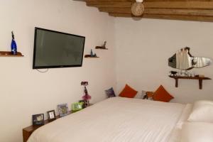 圣克里斯托瓦尔Ideal y linda casita en San Cristóbal-Galápagos的卧室配有白色的床和平面电视。