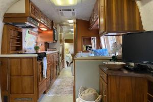 博福特Beautiful Airstream, Beaufort SC-Enjoy the Journey的一个带木制橱柜和电视的大厨房