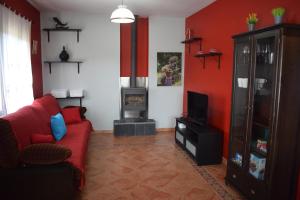 阿维拉La Casa del Colmao的客厅设有红色的沙发和壁炉