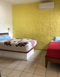 马萨特兰Hotel Perla Mazatlan的一间卧室设有两张床和黄色的墙壁