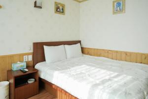 西归浦市君姆海桑帕克特尔度假屋的一间卧室配有一张大床和木制床头板