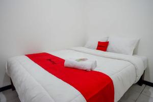 JatingalehRedDoorz near GOR Jatidiri Semarang的卧室配有红色和白色的毯子,位于床上