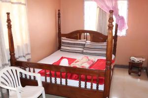 坎帕拉Luwafu Guest House的一间卧室配有木床和白色椅子