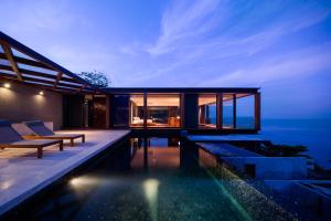 卡马拉海滩The Naka Phuket, a Member of Design Hotels - SHA Extra Plus的现代房子,晚上设有游泳池