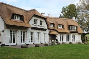 欧迪尼斯Villa Monceau的一座带茅草屋顶的大型白色房屋