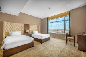哈伊勒Suknai Royal Hotel的酒店客房设有两张床和窗户。