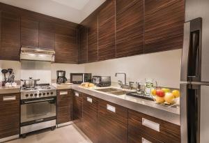 马尼拉Aruga Apartments by Rockwell Makati的厨房配有木制橱柜和一个带水果的盥洗盆。