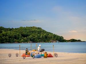 富国New World Phu Quoc Resort的坐在海滩上的男人和孩子
