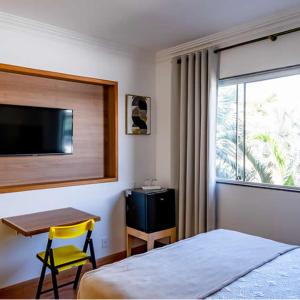 瓦索拉斯Bliss Hotel Vale do Café的一间卧室配有一张床、一张书桌和一台电视