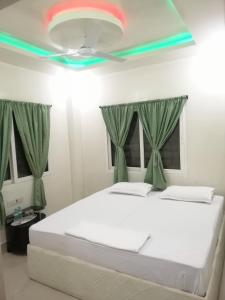 菩提伽耶RAJHAT MARANAO House的一间卧室配有一张带绿色窗帘的床和天花板