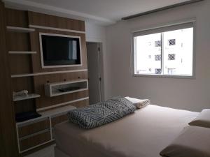 巴拉奈里奥-坎布里乌Apto alto padrão的一间卧室设有一张床、一台电视和一个窗口。