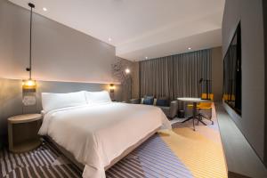 新山Holiday Inn Johor Bahru City Centre, an IHG Hotel的酒店客房设有一张大床和一张桌子。