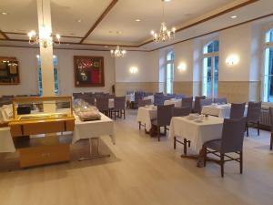 迈林根哈斯里山林小屋的餐厅设有白色的桌椅和窗户。
