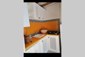 突尼斯Dar El Halfaouine的小厨房配有白色橱柜和橙色瓷砖