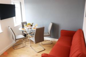WealdstoneModern Newgate Apartments - Kingsbury Underground, All Local Amenities on Your Doorstep的一间带桌子和红色沙发的用餐室