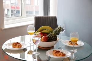 WealdstoneModern Newgate Apartments - Kingsbury Underground, All Local Amenities on Your Doorstep的玻璃桌,放上一碗水果和酒
