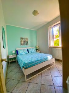 托雷坎内Brezza di Mare的一间卧室配有一张带蓝色床单的床和一扇窗户。