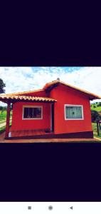 卡皮托利乌Acomodação chalé entre capitolio e escarpas do lago的一座红色的房子,在院子里设有两扇窗户