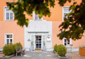 尤登堡JUFA Hotel Judenburg的一座白色和橙色的建筑,前面设有长凳